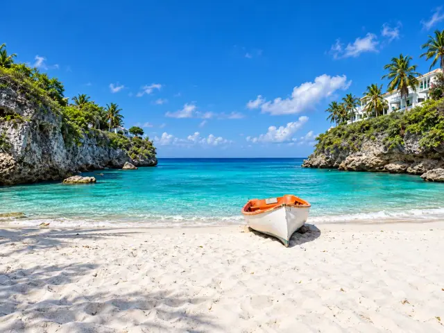 White rowboat on a sandy beach beside a turquoise tropical cove